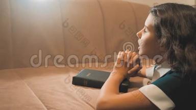 小女孩在夜里祈祷。 小女孩用手祈祷。 小女孩圣经在生活方式中祈祷圣经